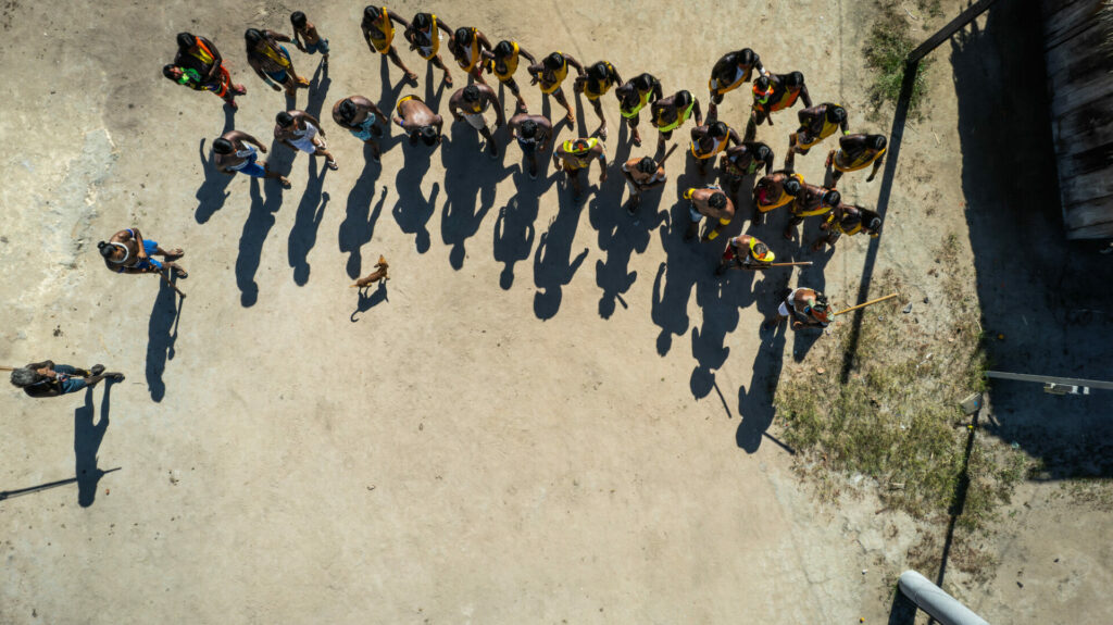 Indigenous group - environmental defenders - stood together with shadows cast in front of them 