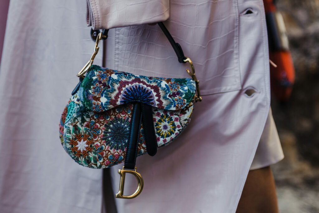 pre-loved Dior saddle bag carried by woman wearing raincoat