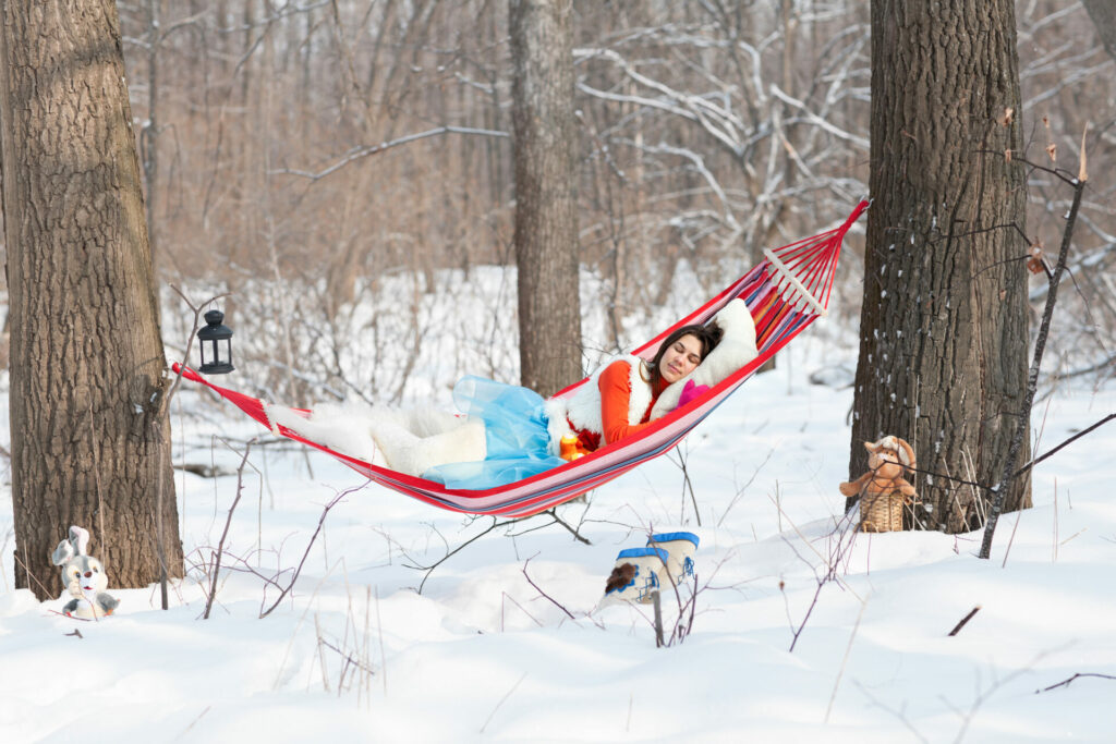 woman in hammock catching up on sleep in the snowy forest in finland