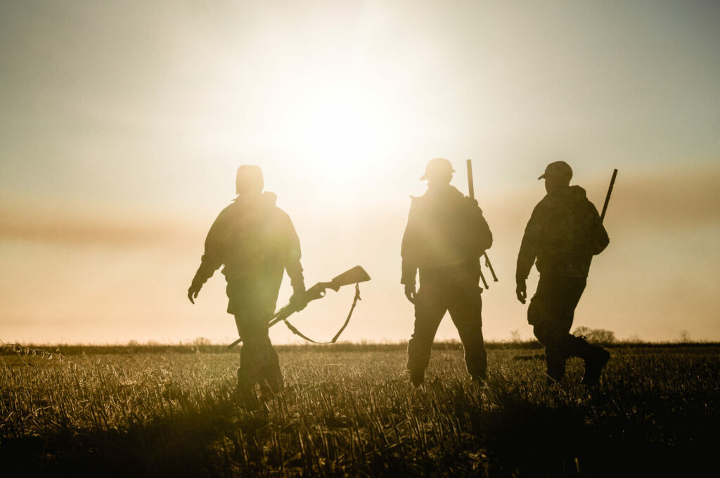 men with guns walking at sunrise 