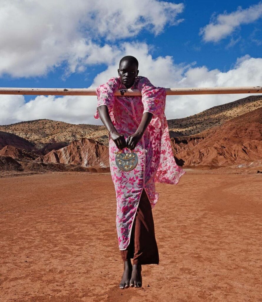 african lady hangs on bar with handbag in red desert 