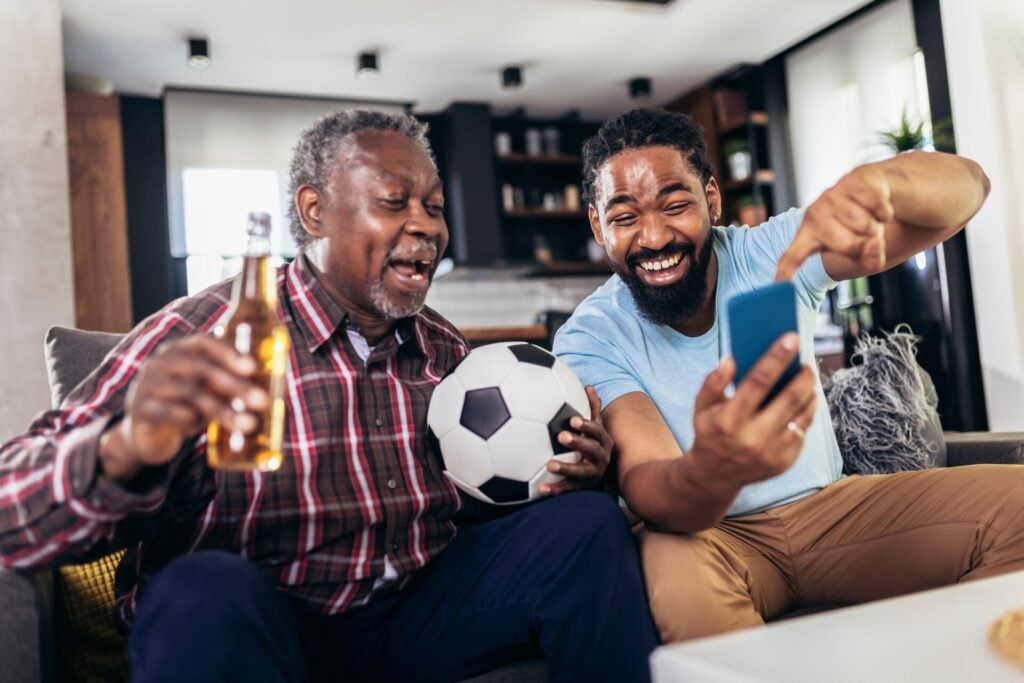 Father and son laughing and betting on a football game