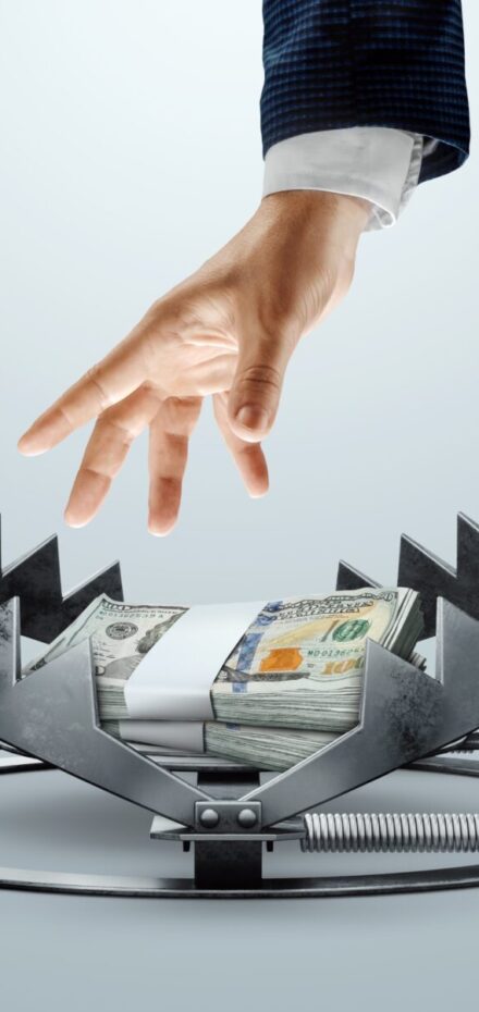 money in a trap with businessman reaching for it - concept of dangers of being rich and successful