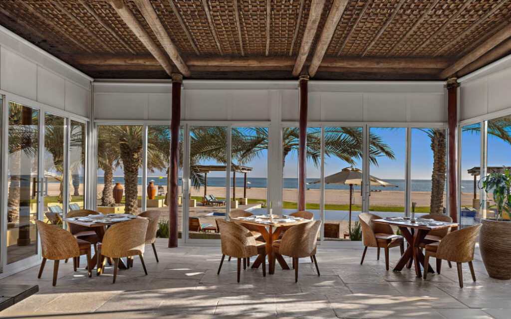 a room with tables and chairs and a beach view