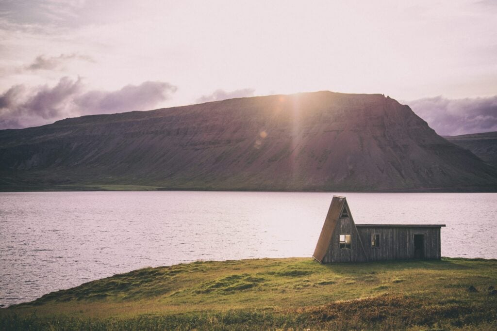 Tiny house on the edge of a fjord with pink sky