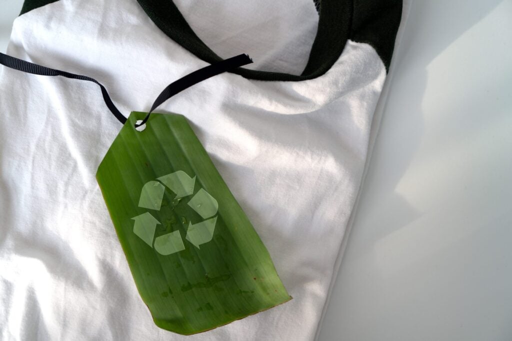 a green recycle tag on a white and black t-shirt representing the eco-myths perpetuated by the fashion industry