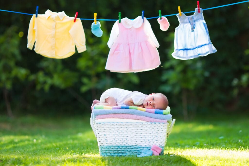 baby lying on a laundry basket under a washing line