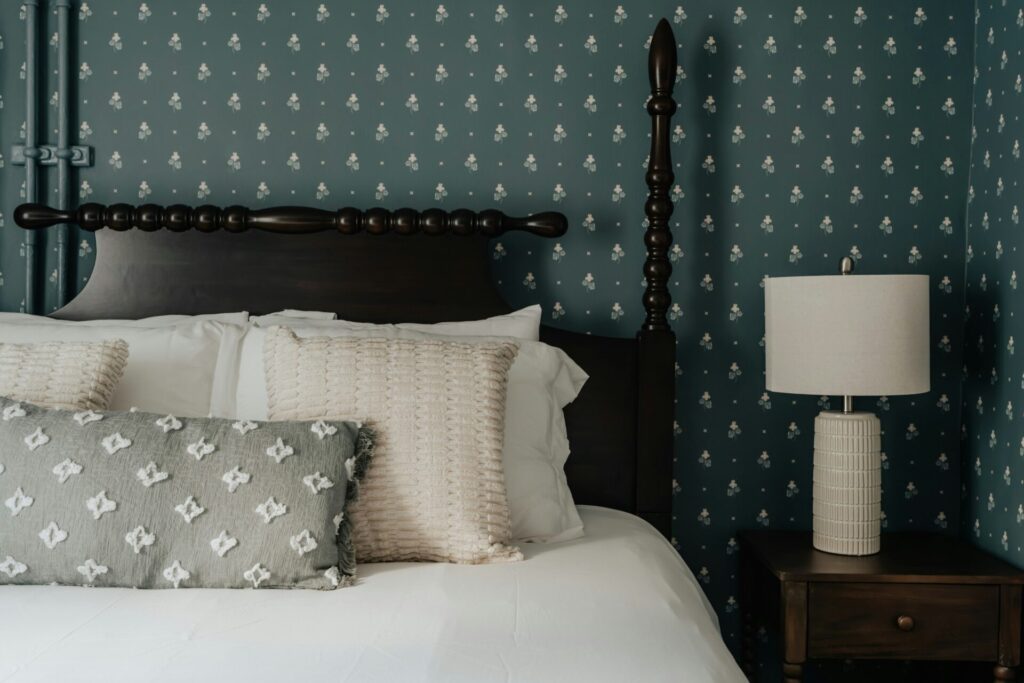 bedroom with green patterned wallpaper in background and white lamp