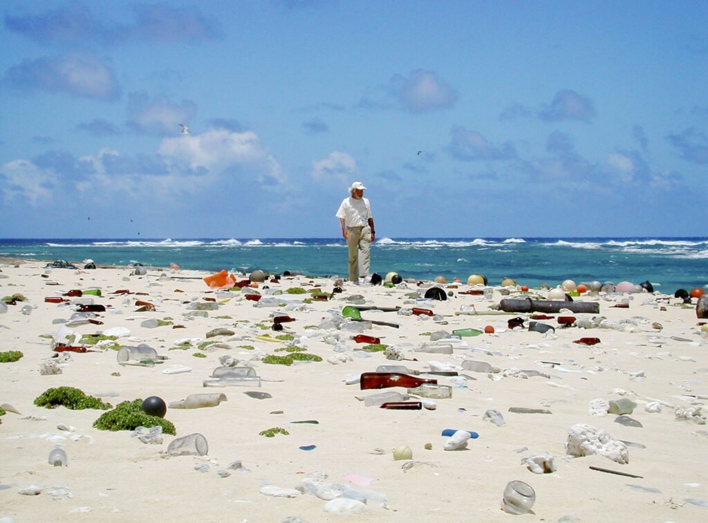 Jean-Michel Cousteau collecting ocean litter on a beach in Hawaii