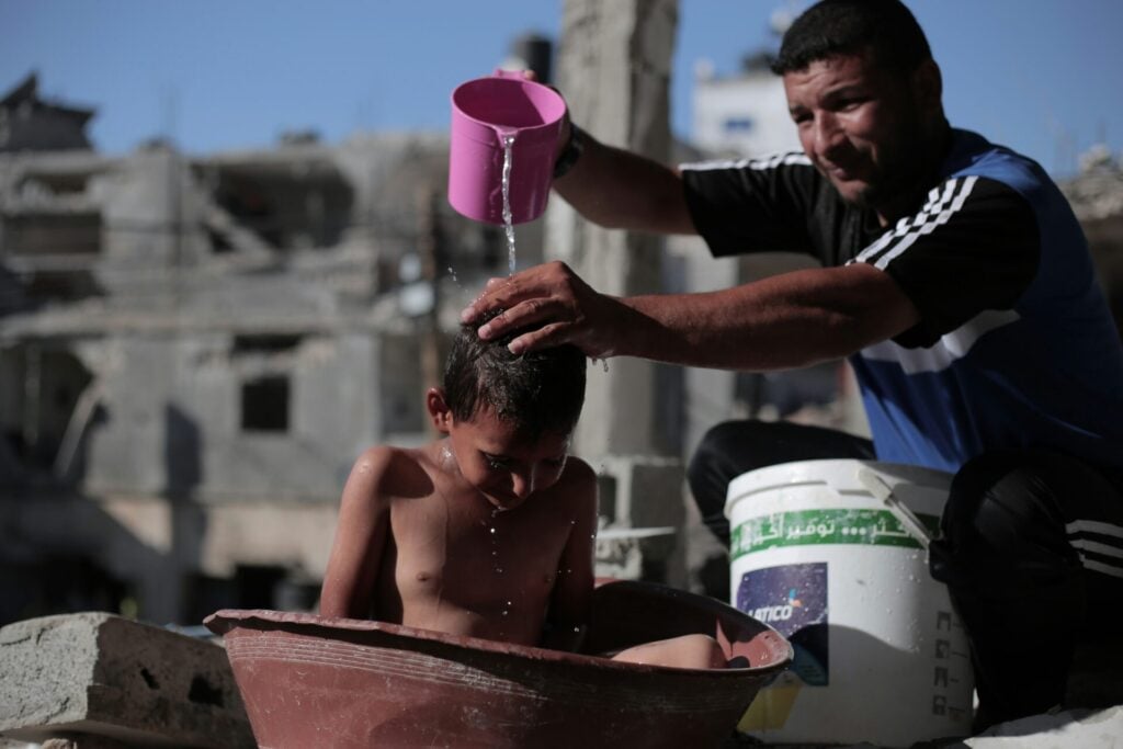 child being washed in bucket in gaza