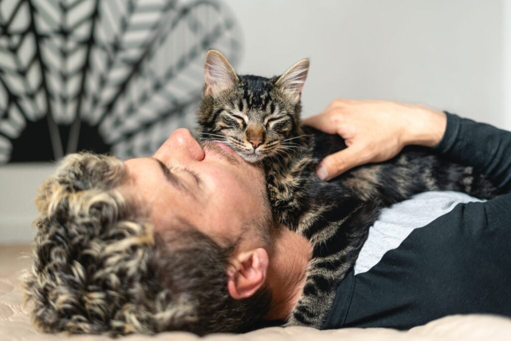 Man with emotional support cat on his chest lying on the ground