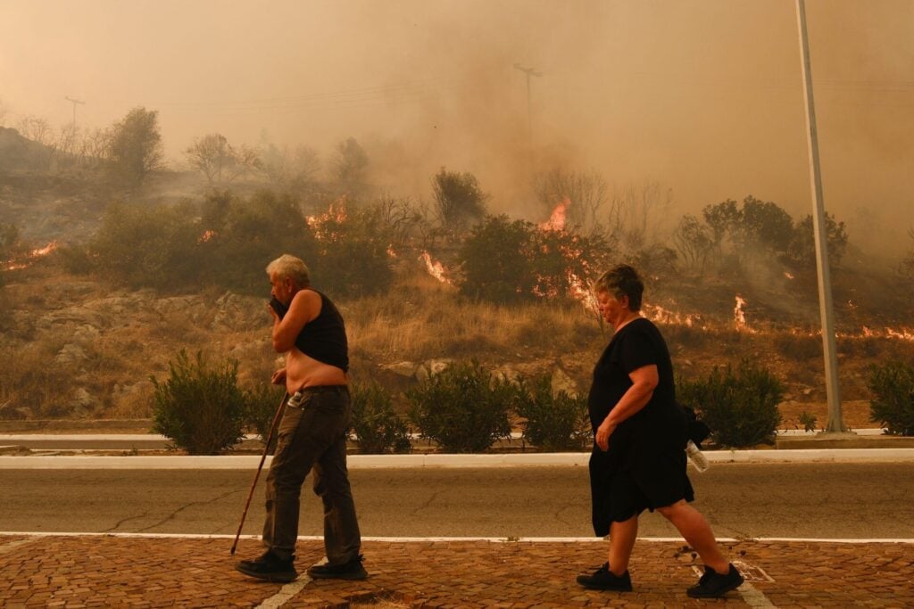 elderly couple walking through fires as heatwave hits Greece