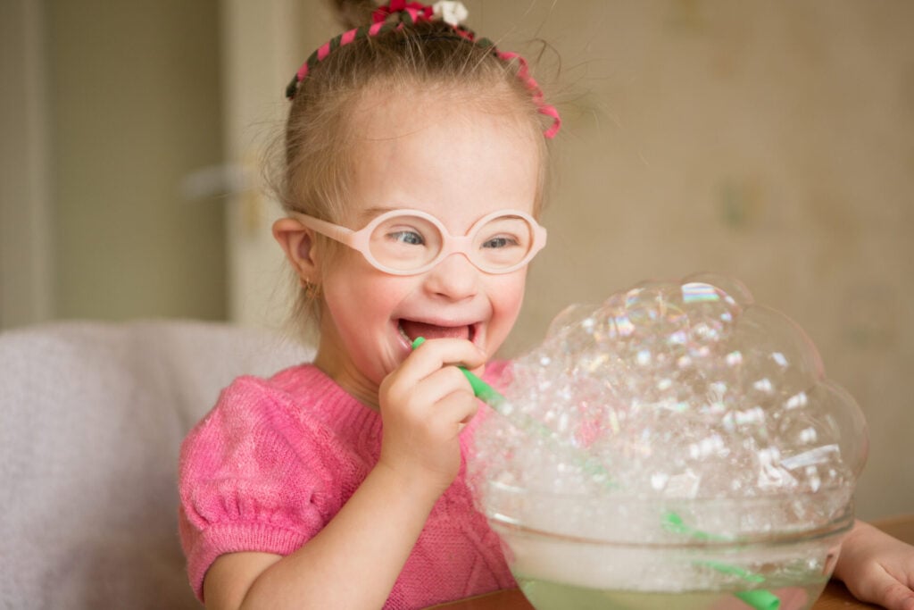 Child with downs syndrome blowing bubbles 