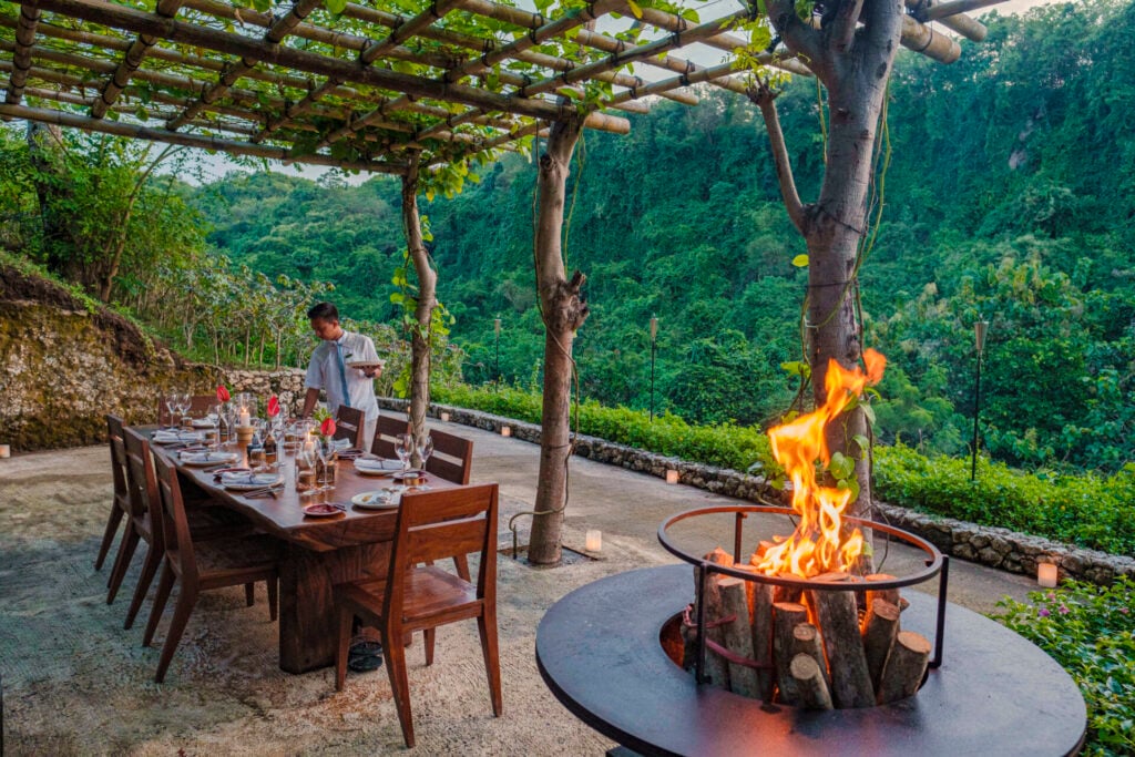 Outdoor dining with fire and greenery