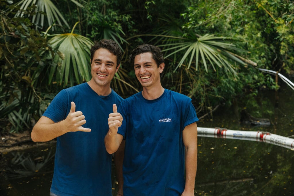 The Bencheghib brothers satnd with their thumbs up in a river in Indonesia 