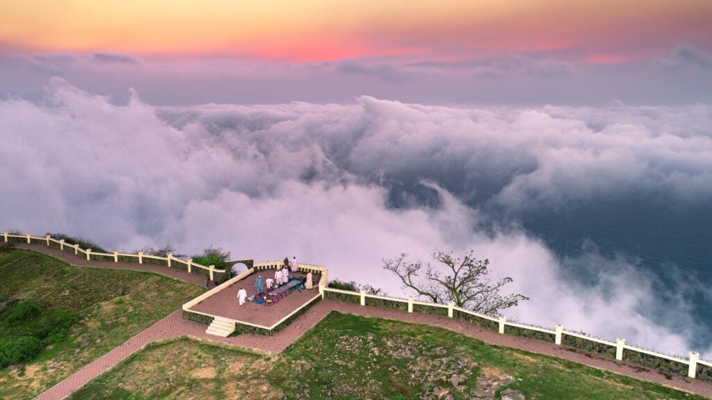 people on a cliff top viewing point overlooking clouds in Salalah