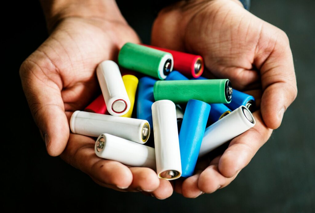a person holding a pile of batteries