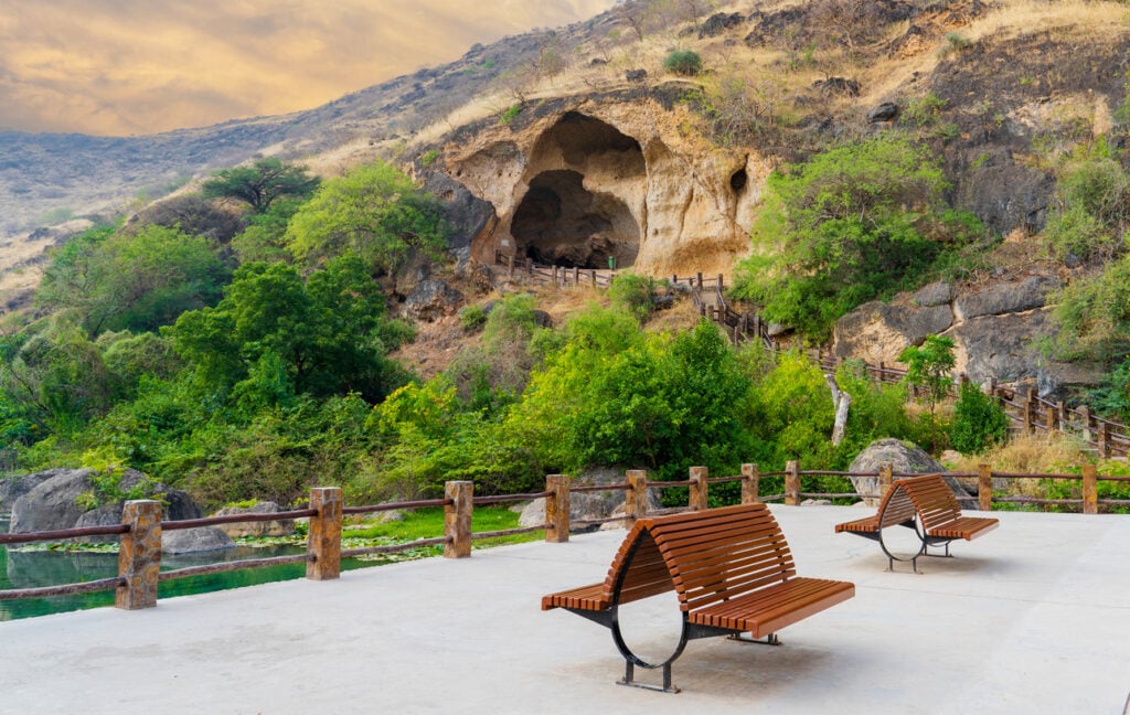 benches on a walkway near a cave in Salalah