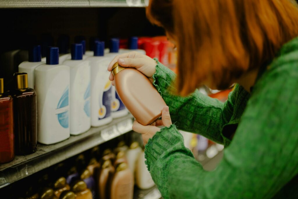 a woman holding a bottle of shampoo and inspecting the label