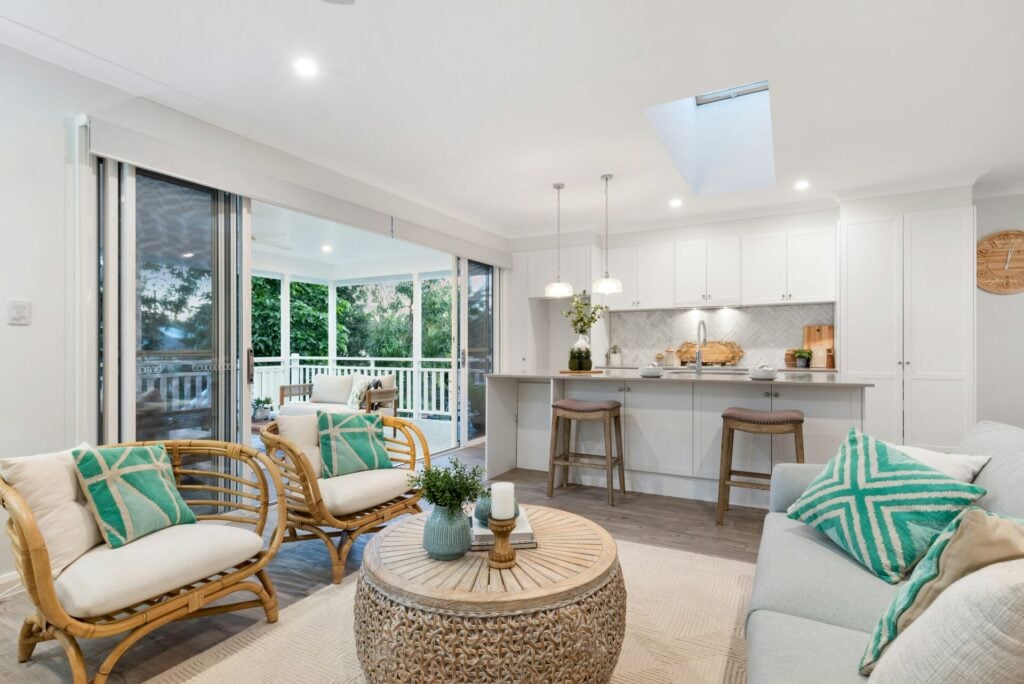 a living room with a table and chairs and sliding doors looking out on a wide balcony 