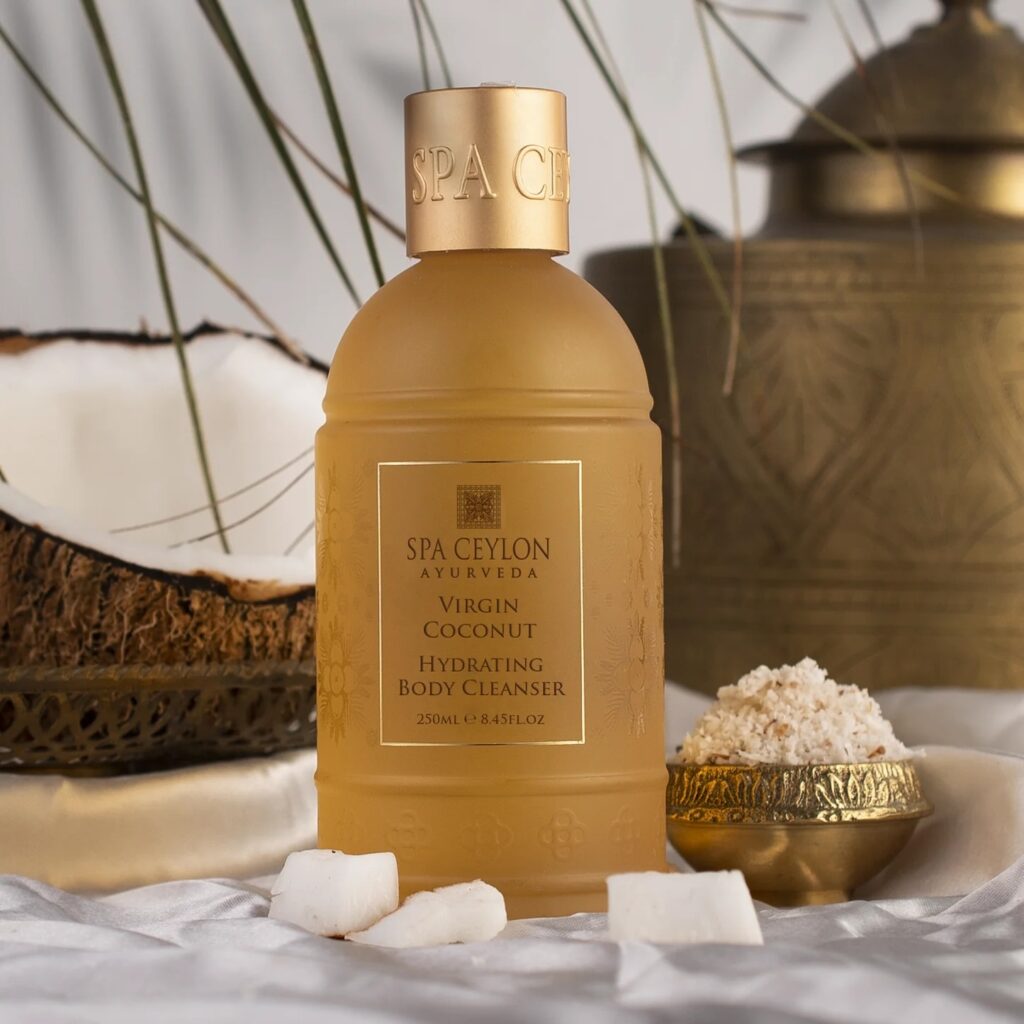 Bottle of Spa Ceylon hydrating body cleanser with coconut lying nearby