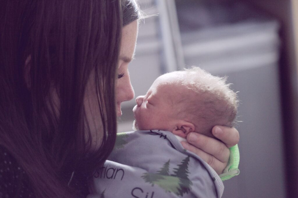 Woman holding a newborn baby gently.