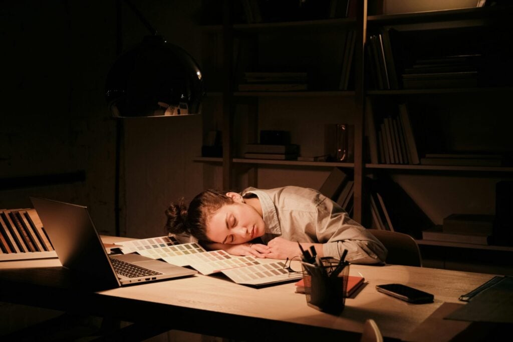 Person resting on a cluttered desk.