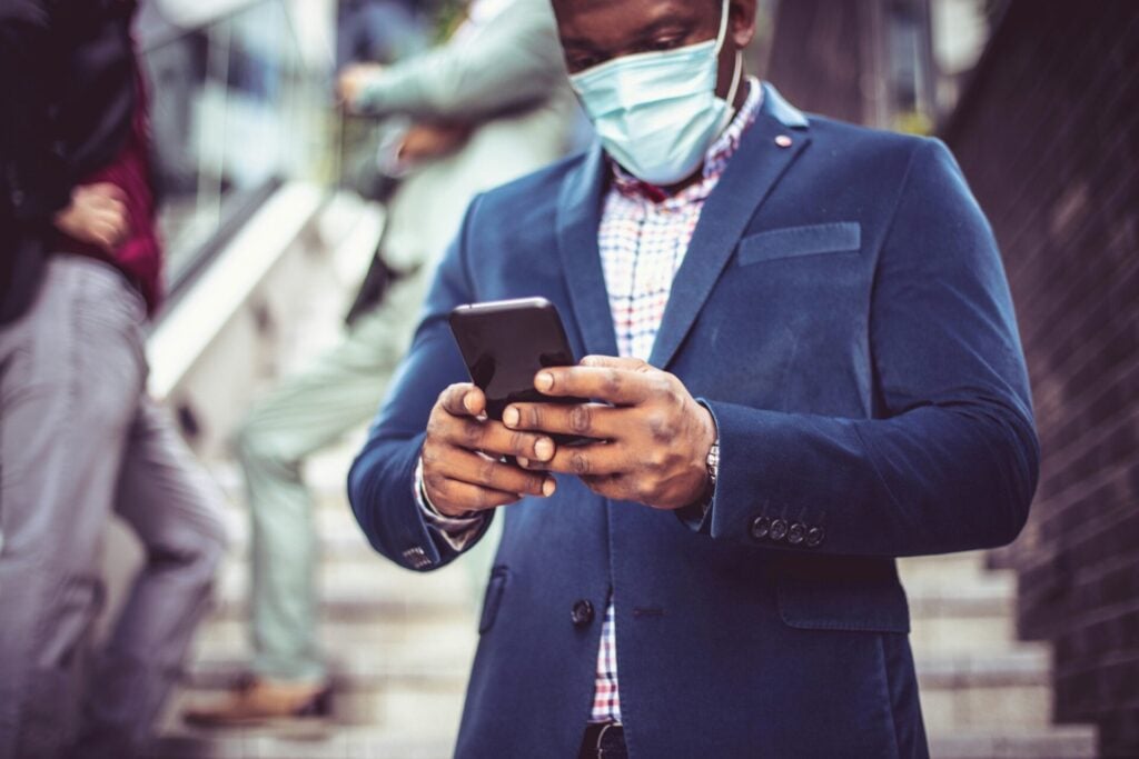 man looking at phone during the covid pandemic wearing a mask