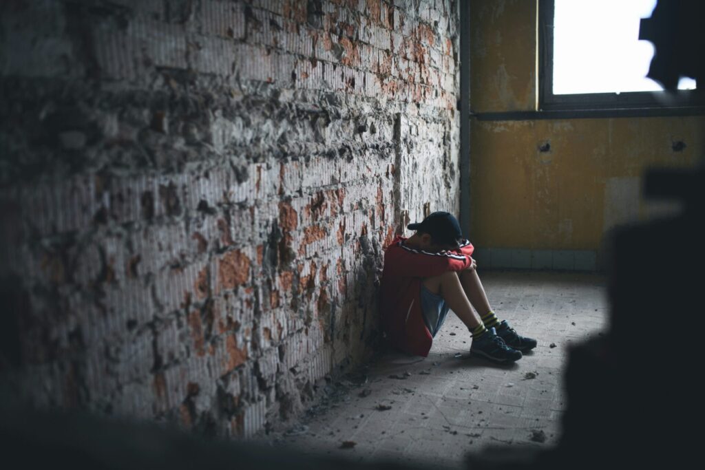Lonely child sitting against wall illustrating a child with PTSD 