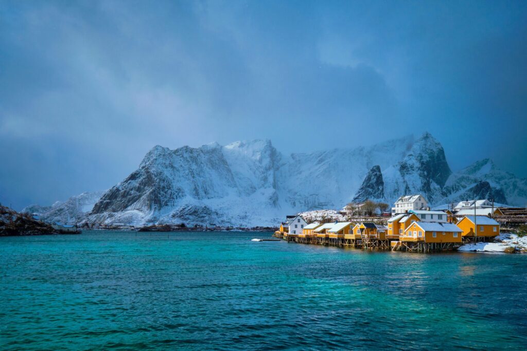 Snowy mountains beside colourful fishing village as eco-friendly travel destination