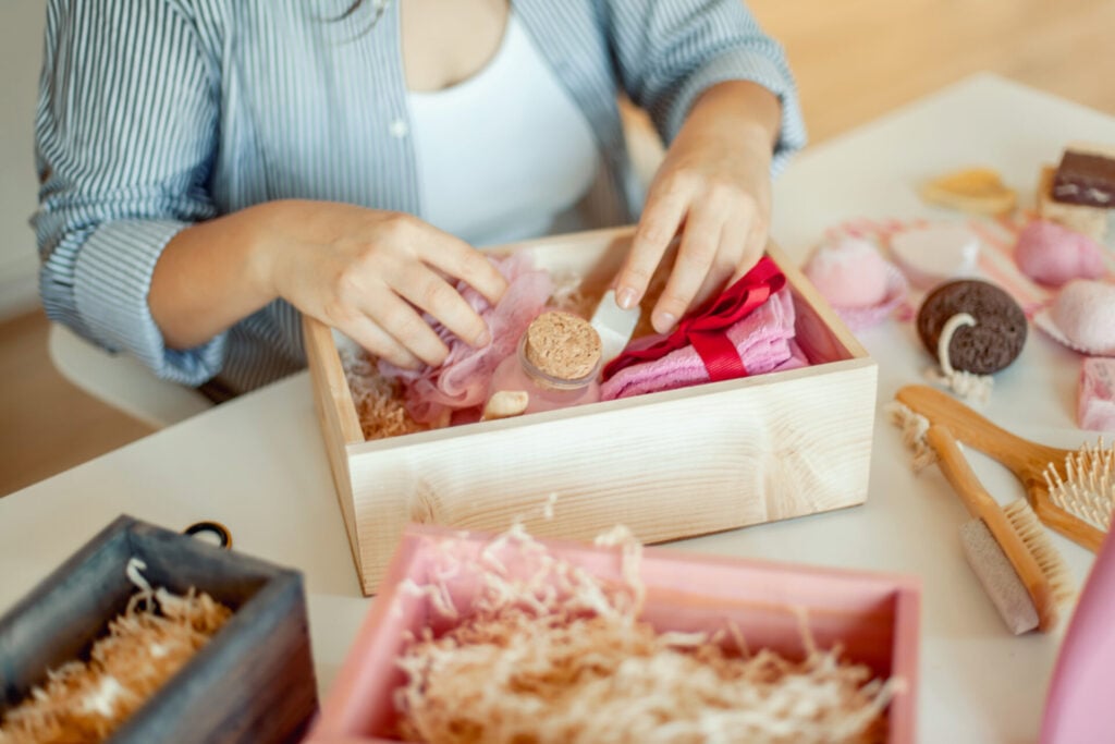 Person arranging items in gift box
