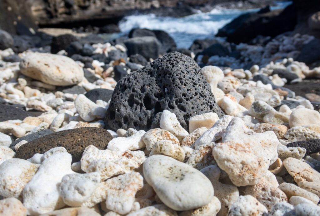 Rocky beach with white coral stones and a lava rock 