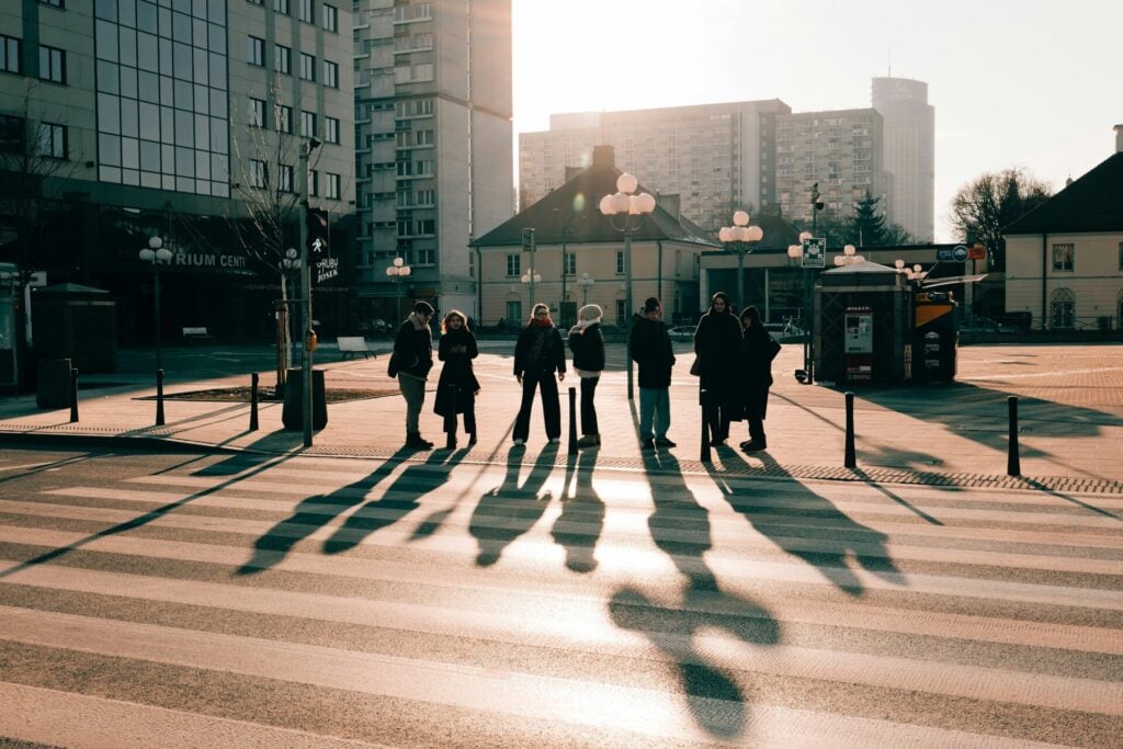 People crossing street with long shadows