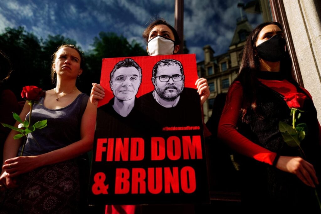 Protesters holding signs and roses.