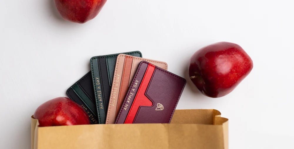 Colorful wallets made from vegan leather next to red apples
