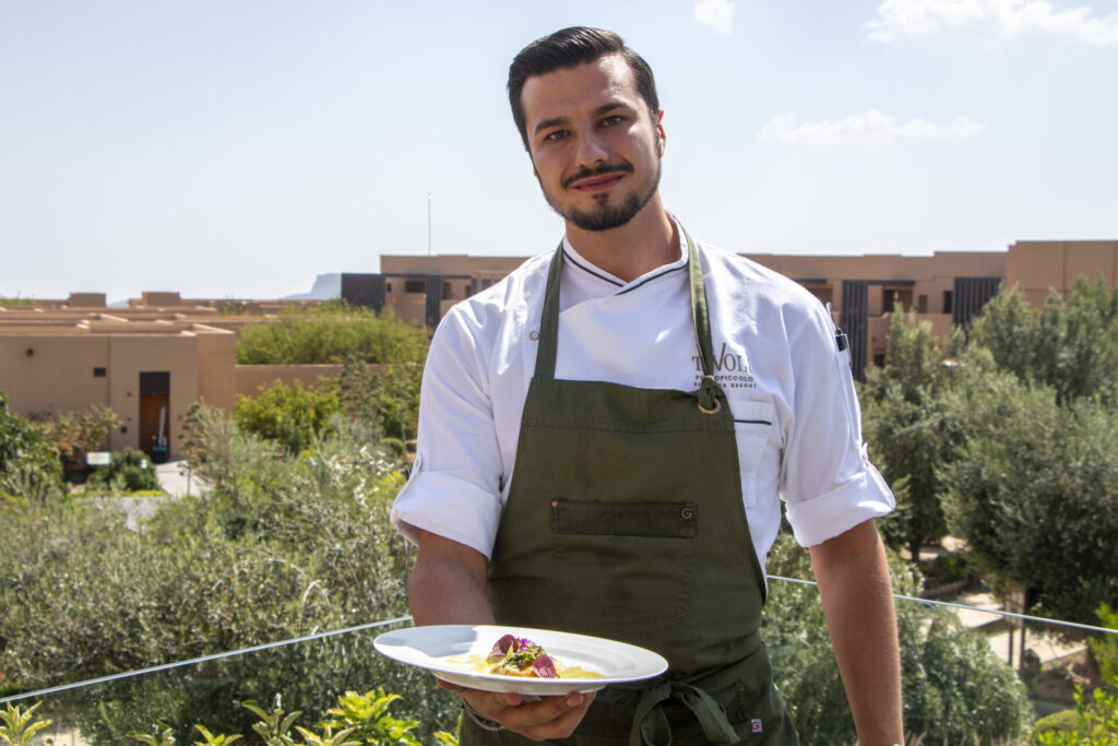 Chef presenting a gourmet dish outdoors.