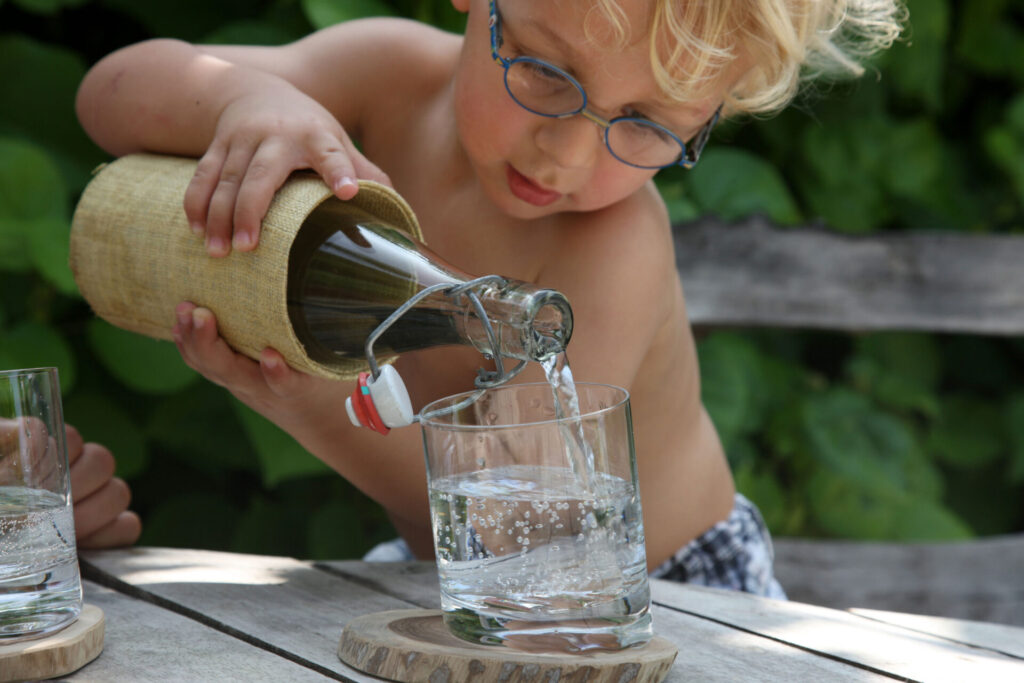 Child pouring water into glass.