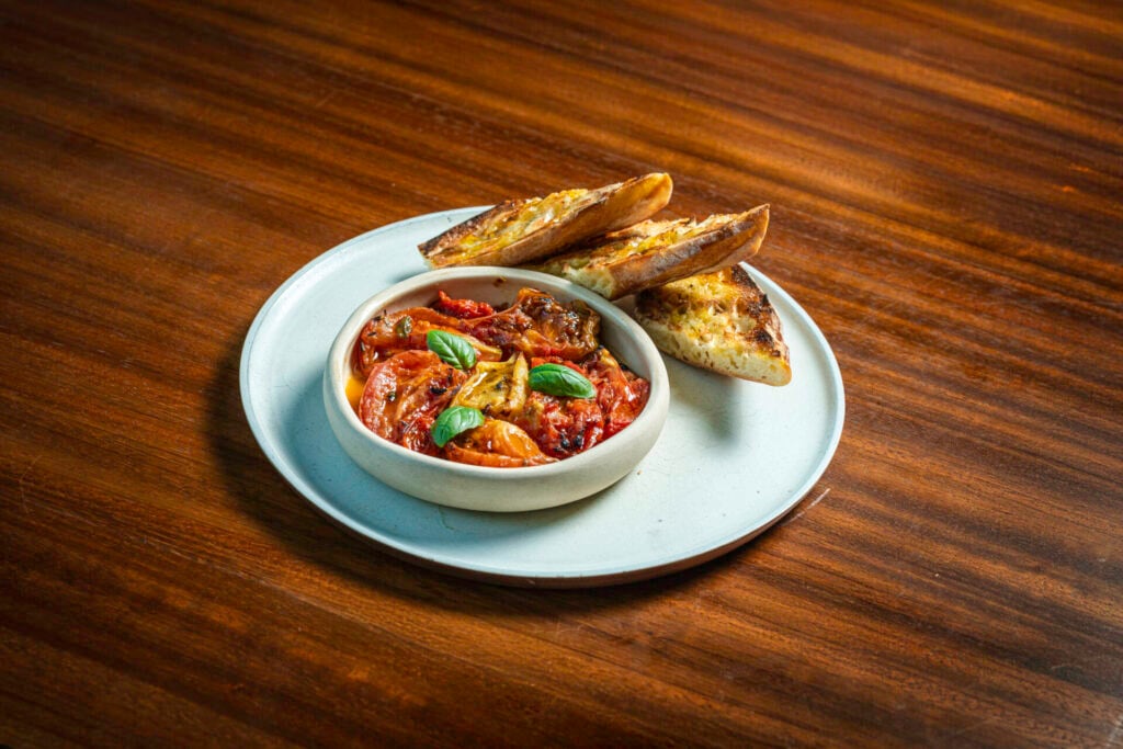 a colourful plate of heirloom tomatoes, grilled bread, and basil