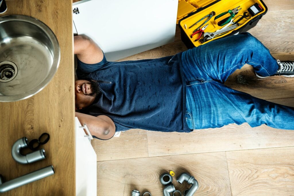 Man fixing plumbing under sink