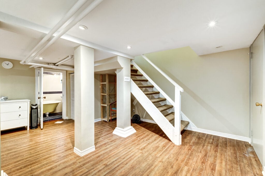 Spacious basement with wooden flooring.