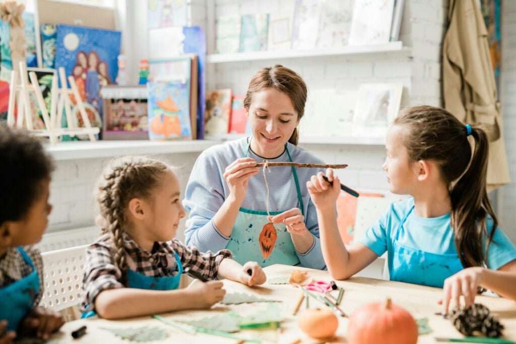teacher demonstrating compassionate teaching by smiling and interacting with her pupils in an art 