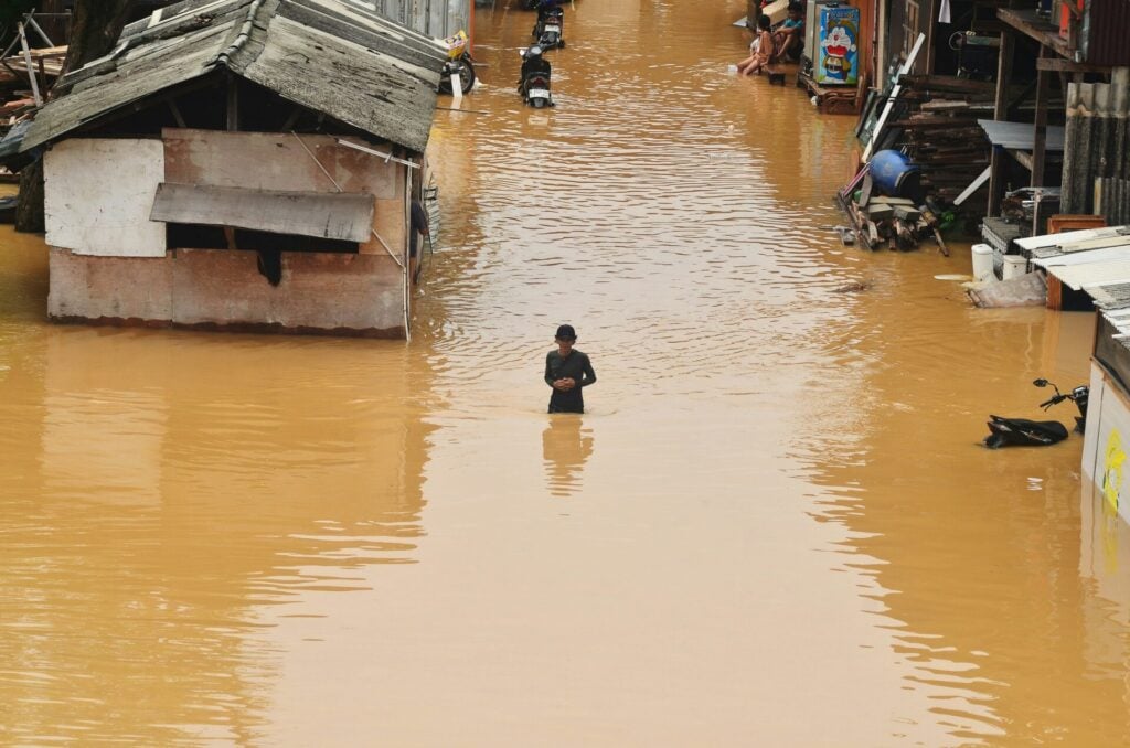 Man standing in flooded street in Asia 