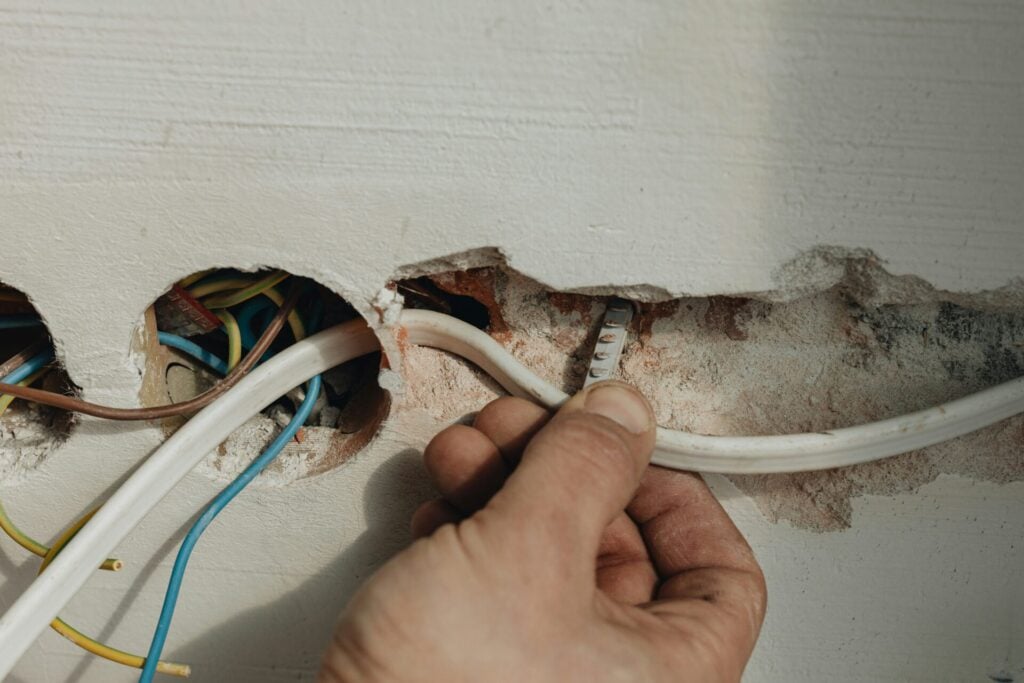 Hand connecting electrical wires in wall