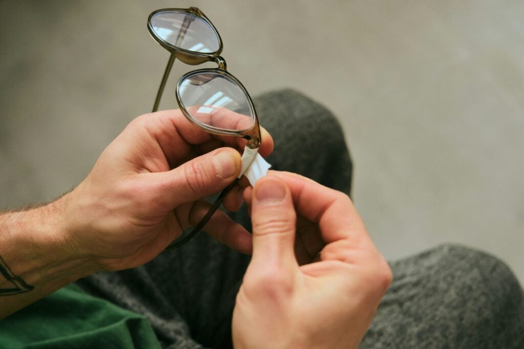 man putting tape on broken glasses