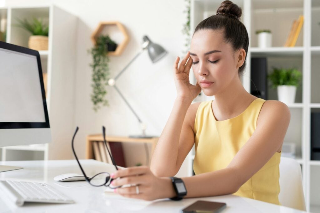 woman with glasses in hand with headache