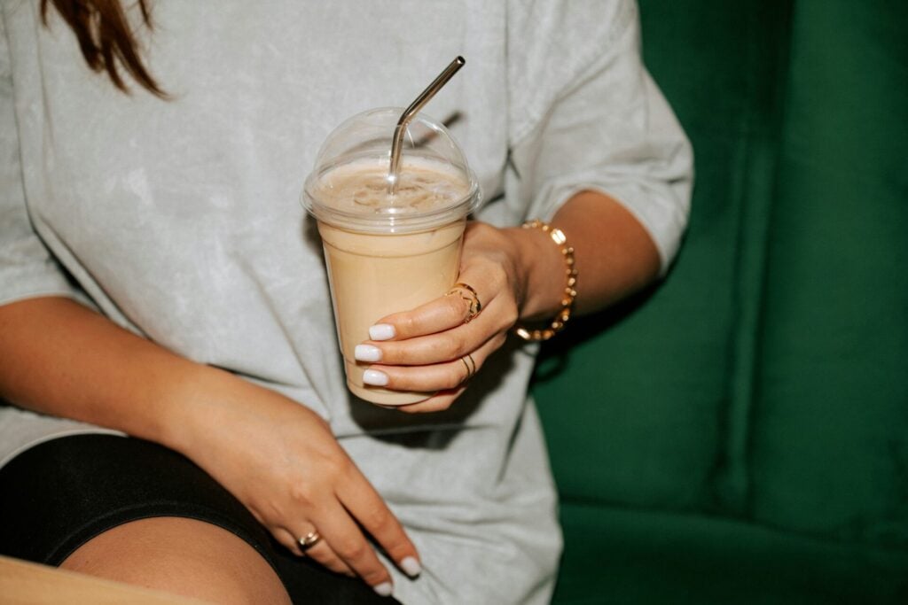 Person holding iced coffee in a plastic container which will be banned in dubai in 2026 as part of their plastic reduction efforts