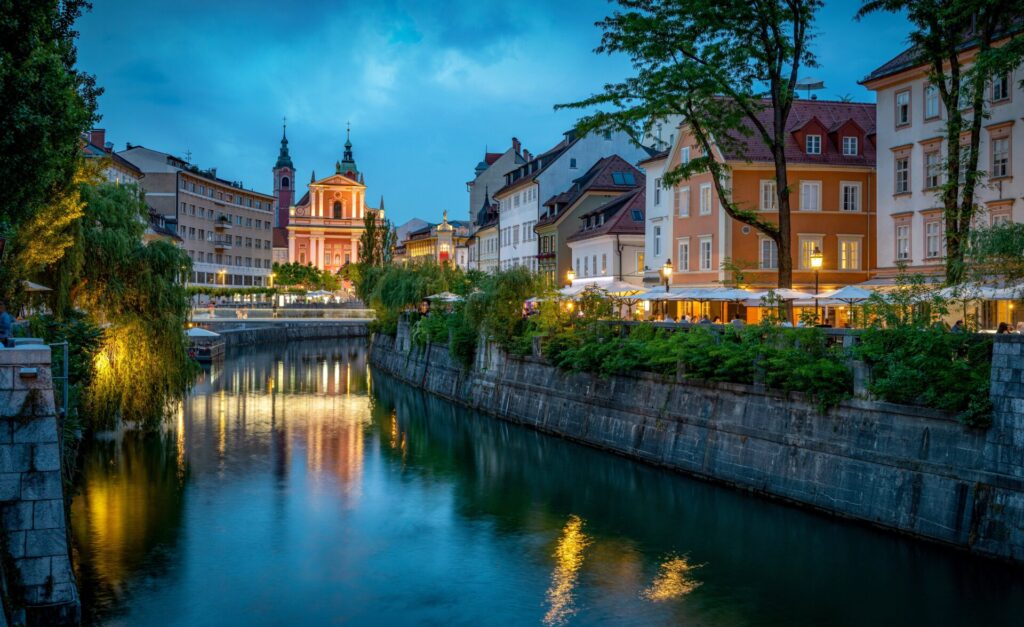 canal at dusk with eateries running either side and street lights reflecting on the water
