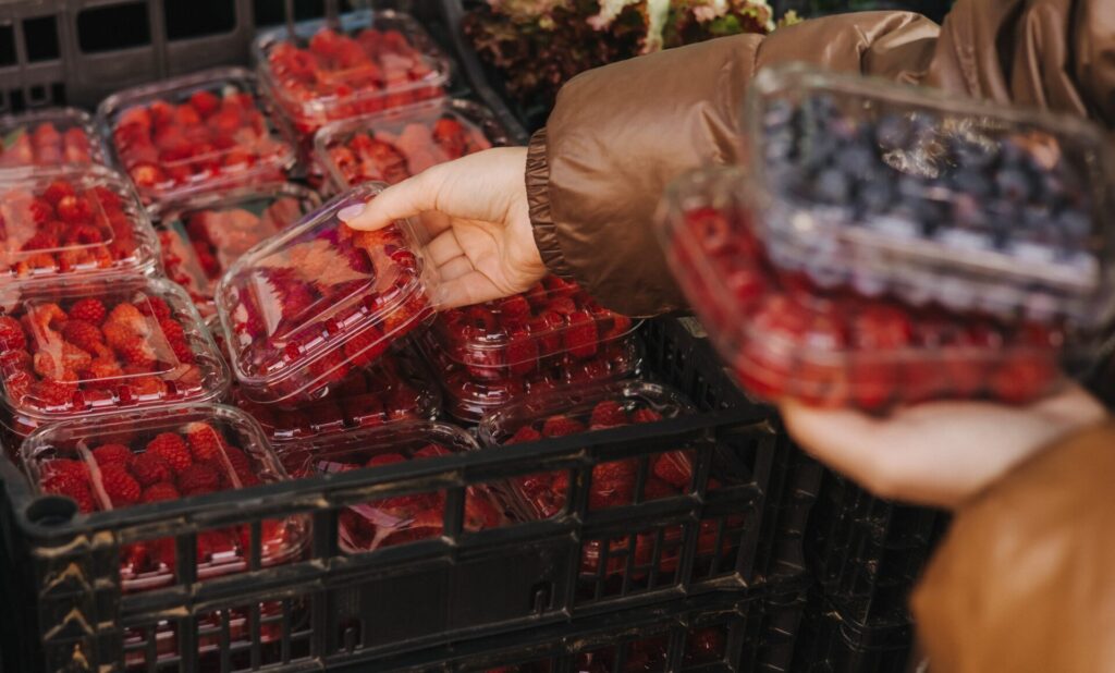 Hands selecting berries from containers