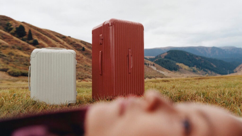 suitcases in scottish highlands and woman lying near them on the ground 