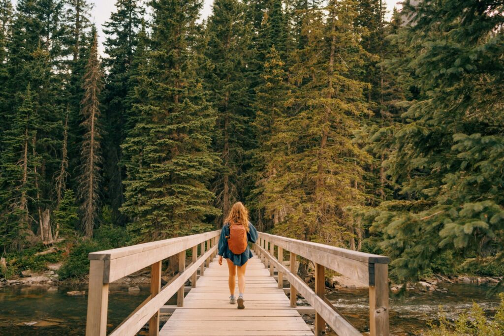 woman walking in the woods over a bridge 